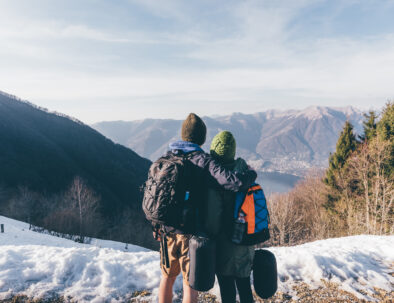 Rear view of hiking couple looking out over lake and mountains, Monte San Primo, Italy